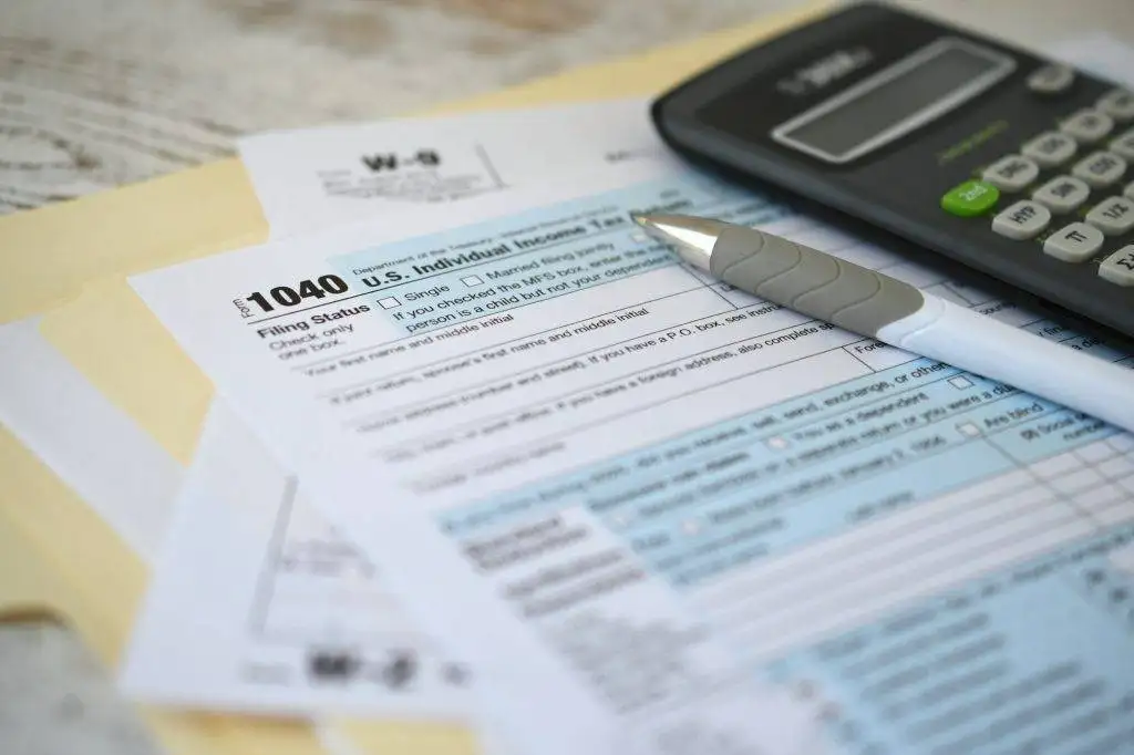 IRS 1040 Tax return form with ink pen and calculator. Filing income taxes before the deadline.